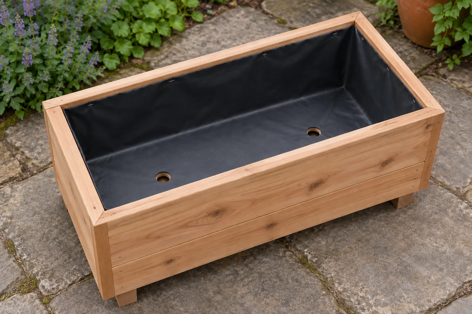 A cedar planter lined with black plastic and open outlets through the liner and timber base