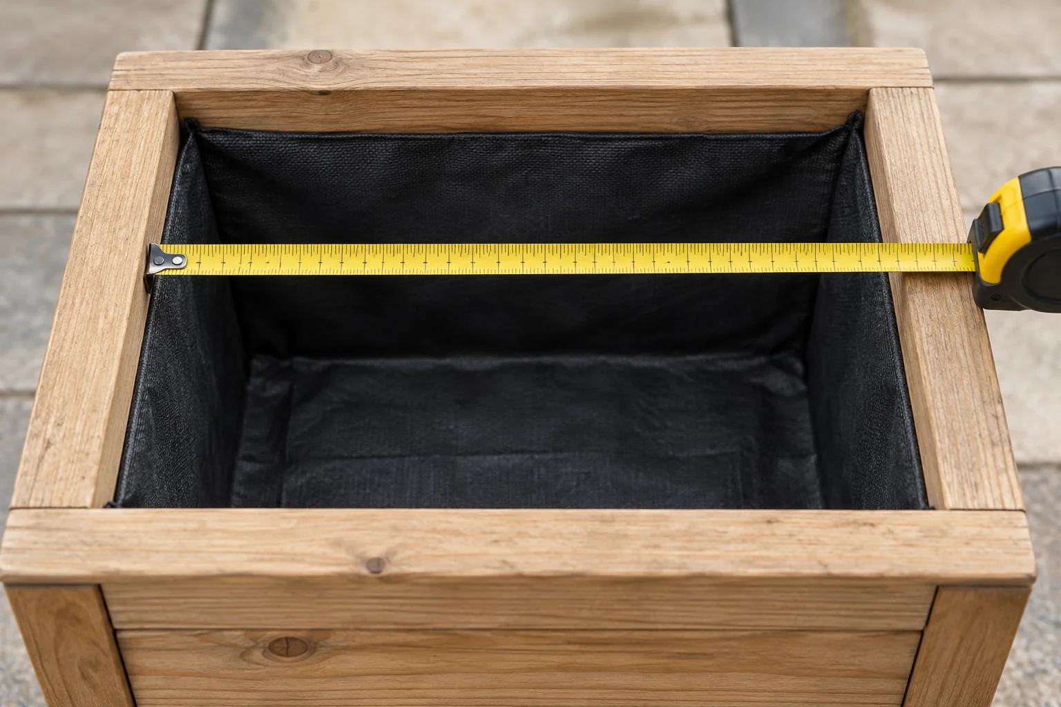 Tape measure spanning the inside width of an empty timber planter