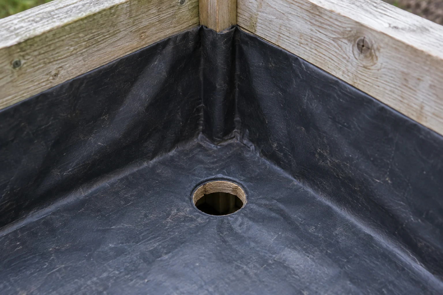 A clear opening through a planter liner aligned with the hole in the timber base