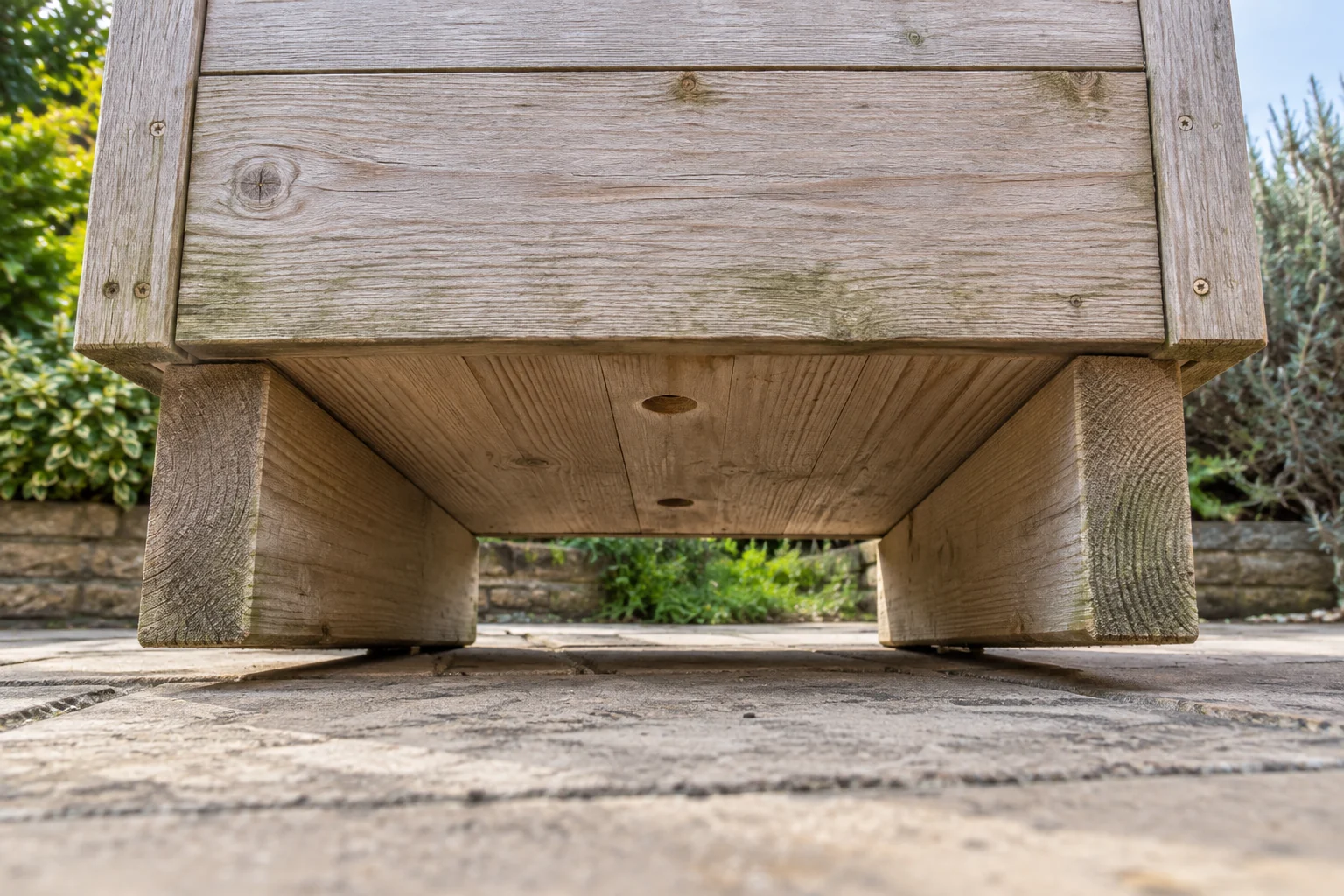 Drainage holes between the timber supports underneath a raised planter